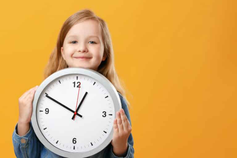 A cute little girl holding a big clock